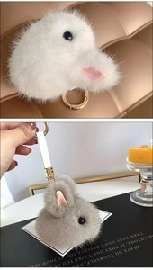 Close-up of plush rabbit head keychains in white and grey with golden metal ring details