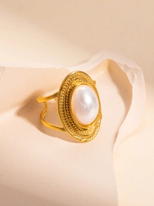 Macro detail of vintage gold pearl ring with textured relief on beige stone surface