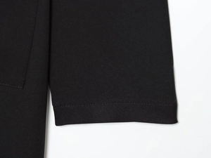 Vue détaillée montrant la couture plate professionnelle sur le tissu noir de la robe midi