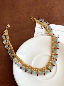 Détail du collier de perles fait main avec perles bleues et dorées sur assiette blanche