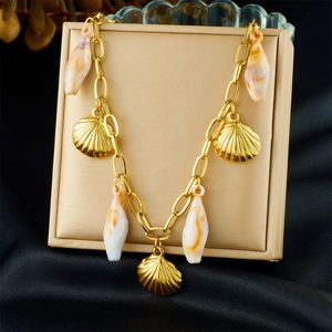 Detailed shot of a gold shell charm bracelet hanging over a silk champagne display box