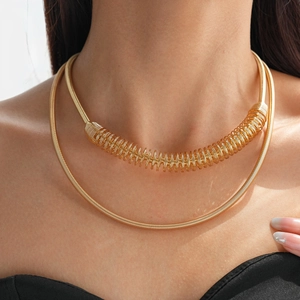 Gros plan d'un collier double épaisseur en métal doré avec chaîne ressort sur mannequin