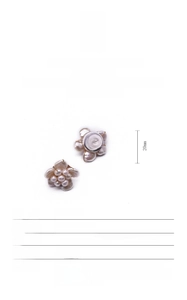Detail of flower shaped earrings with natural baroque pearls on 18k gold plated base
