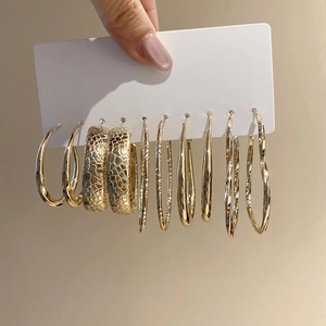 Close-up of five pairs of textured gold C-shaped hoop earrings on a display card