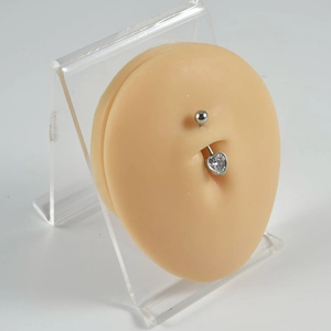 Macro shot of silver heart-shaped zircon belly ring on a silicone display model