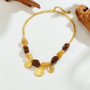 Retro gold chain necklace with amber resin beads and embossed circular pendants on wood