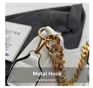 Detailed macro view of bright gold metal snap hook and textured chain on a white bag