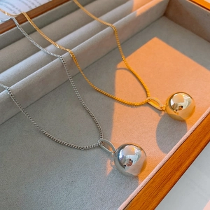 Macro detail of gold and silver minimalist ball pendants on a velvet jewelry tray
