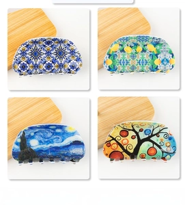 Detail view of 8cm hair claw clips with star night and floral art patterns on wood