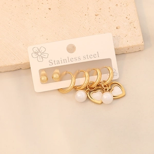 Détail macro du lot de boucles d'oreilles en acier doré avec perles blanches et cœurs