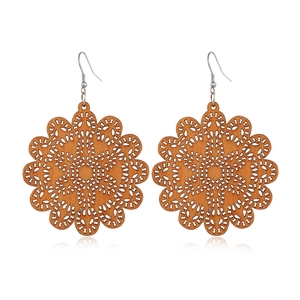 Macro detail of hollow mandala pattern on brown wooden earrings with metal hooks