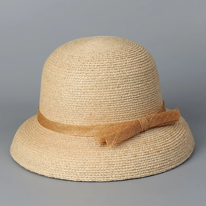 Detail of raffia woven sun hat featuring a dome crown and elegant mesh ribbon bow