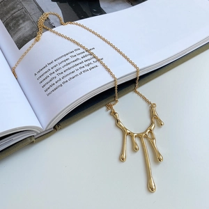 Macro shot of liquid lava pendant necklace in 18K gold finish over a white magazine