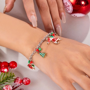 Detailed view of Christmas charm bracelet with Santa and tree pendants on model's wrist