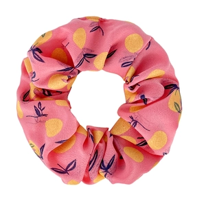 Detail of pink fabric scrunchie featuring vibrant yellow lemon and navy leaf patterns