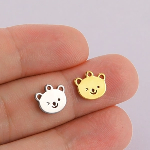 Macro shot of small gold and silver bear charms for DIY jewelry making held in fingers