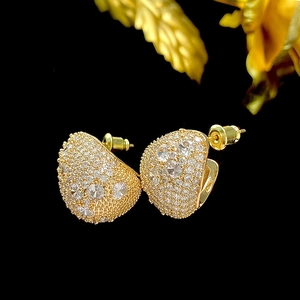 Macro shot of gold teardrop earrings featuring pavé cubic zirconia on black background