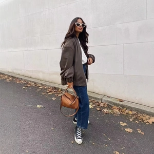 Chic oversized brown bomber jacket styled with blue jeans and fall fashion accessories