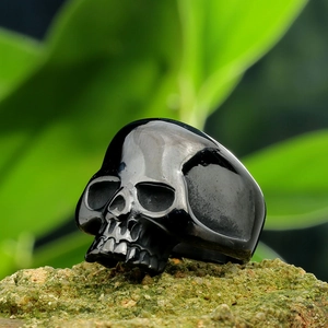 Macro shot of black polished skull ring on a mossy rock with a natural green background