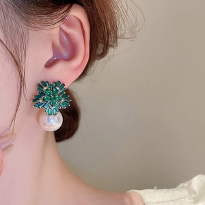 Close-up of floral earrings with green zircons and a large white pearl drop