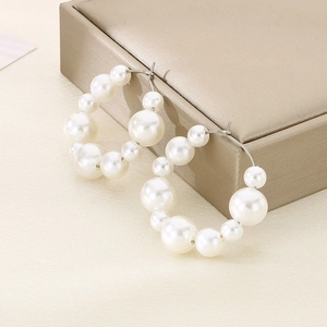 Elegant U-shaped stainless steel hoop earrings featuring white faux pearls on a jewelry box
