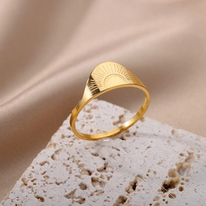 Macro detail of sunburst engraved 18K gold plated stainless steel ring on beige stone