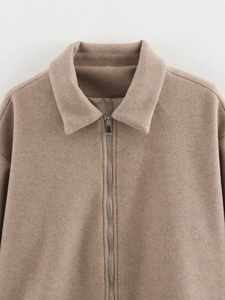 Gros plan du col à revers et du zip métallique sur une veste en tweed décontractée camel