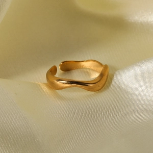 Minimalist golden wave pattern open ring made of stainless steel on silk fabric