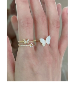 Detailed view of three gold rings with butterfly motifs and diamonds on a hand