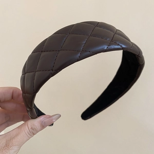 Close-up of a brown quilted leather headband featuring a vintage wide padded design