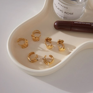 Elegantes 6er-Set goldene Herz- und Rosenohrringe auf einem luxuriösen Wellentablett