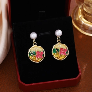Detail of floral enamel drop earrings with red petals, green leaves and pearl studs