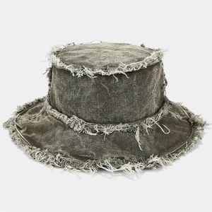 Detailed macro view of distressed denim bucket hat with raw edges and washed texture