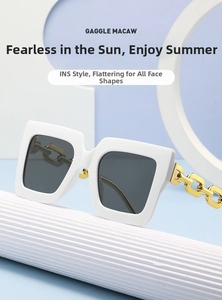 Detalle de gafas de sol cuadradas blancas con patillas de cadena de metal dorado