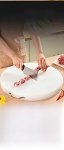 Macro detail of white PE plastic round chopping board with brushed metal U-shaped handle