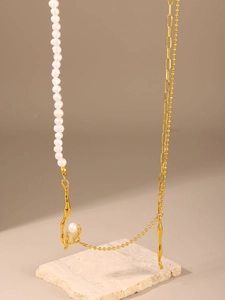 Detailed view of baroque pearl necklace with golden asymmetric chain on stone base