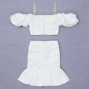 Close-up of white satin two-piece set with pearl straps and tiered ruffle skirt detail