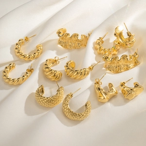 Detail view of assorted 18k gold plated C-shaped hoop earrings on white silk fabric
