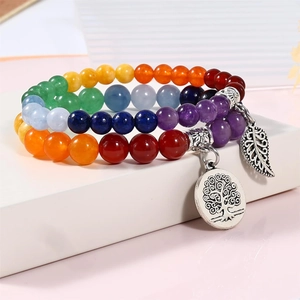 Close-up of tree of life and leaf pendants on multi-color chakra gemstone bracelets