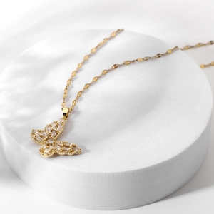 Detail of 18K gold butterfly pendant necklace with sparkling cubic zirconia on a white stand