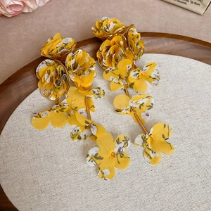 Close-up of yellow floral fabric tassel earrings with intricate white and purple patterns