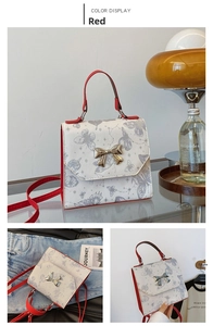 Close-up of butterfly print bag with red straps and gold bow hardware details