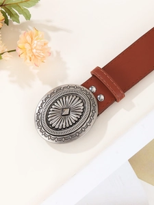 Close-up of vintage brown leather belt with large etched silver oval buckle detail