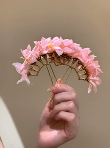 Handheld close-up of pink fabric flower hair pin with golden U-shaped fork pins