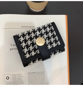 Close-up of houndstooth wallet with gold buckle placed on an architecture magazine