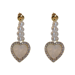 Elegant gold heart earrings with faux pearls and sparkling rhinestones on white background