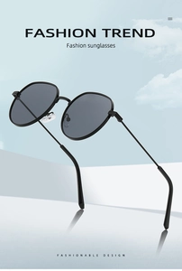 Fashionable black metal sunglasses with grey lenses against a clear blue sky background