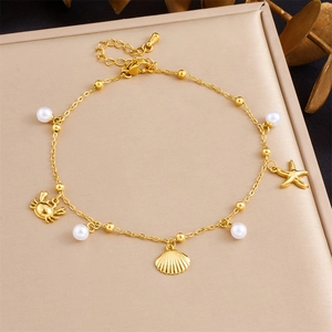 Detail of gold starfish and shell charms with white pearls on a stainless steel anklet