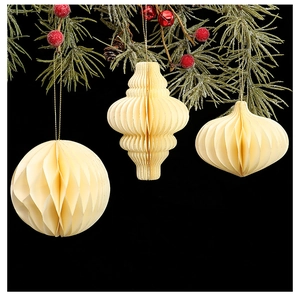 Close-up of cream honeycomb paper Christmas tree ornaments hanging on festive pine branches