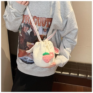 Detail of hand-woven bucket bag with rabbit ears and cute strawberry charm on a model
